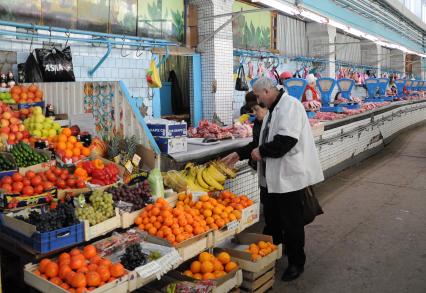 Продавец фруктов показывает покупателю товар.