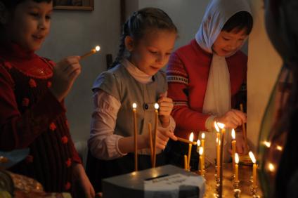 Девочки зажигают свечи в церкви.