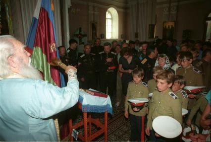 Пожилой священник кропит святой водой курсантов в храме.