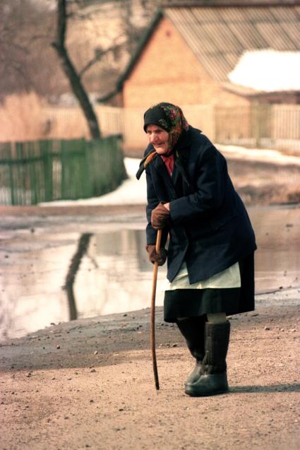 Старуха с палочкой идет по улице.