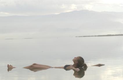 Девушка лежит на воде в Мертвом море.