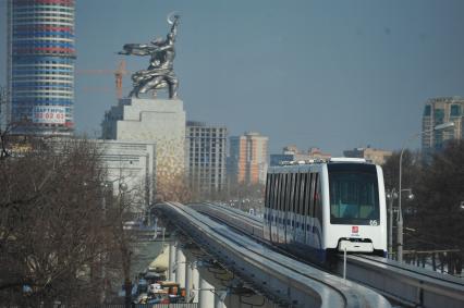 Московская монорельсовая транспортная система (ММТС). На снимке: монорельсовый поезд и памятник `Рабочий и колхозница`.