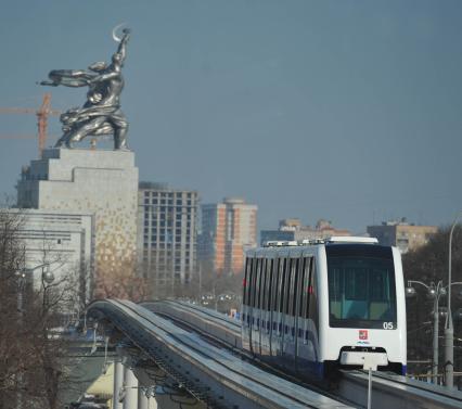 Московская монорельсовая транспортная система (ММТС). На снимке: монорельсовый поезд и памятник `Рабочий и колхозница`.