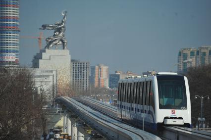 Московская монорельсовая транспортная система (ММТС). На снимке: монорельсовый поезд и памятник `Рабочий и колхозница`.