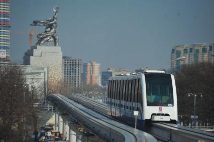 Московская монорельсовая транспортная система (ММТС). На снимке: монорельсовый поезд и памятник `Рабочий и колхозница`.