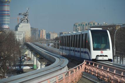 Московская монорельсовая транспортная система (ММТС). На снимке: монорельсовый поезд и памятник `Рабочий и колхозница`.