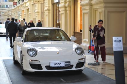 ГУМ. Выставка уникальных автомобилей Porsche, расположенных вдоль первой линии магазина, которая была временно стилизована под `Улицу Porsche`.На снимке: уборщица и автомобиль Porsche.