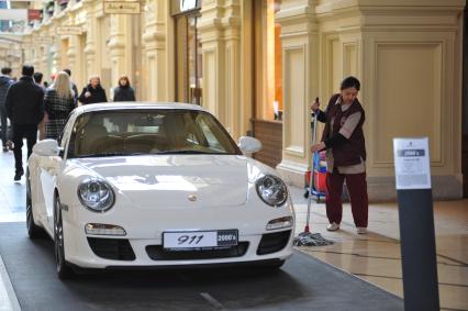 ГУМ. Выставка уникальных автомобилей Porsche, расположенных вдоль первой линии магазина, которая была временно стилизована под `Улицу Porsche`.На снимке: уборщица и автомобиль Porsche.