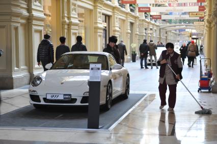 ГУМ. Выставка уникальных автомобилей Porsche, расположенных вдоль первой линии магазина, которая была временно стилизована под `Улицу Porsche`.На снимке: уборщица и автомобиль Porsche.