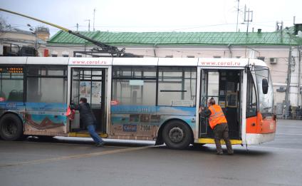 Двое мужчин толкают троллейбус.