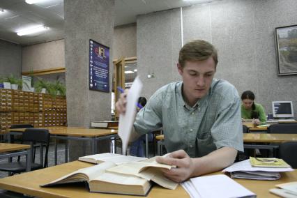 Молодой человек в читальном зале штудирует учебники.