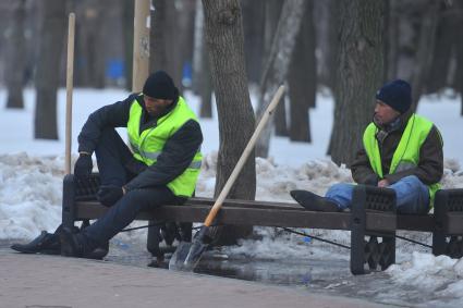 Гастарбайтеры сидят на лавочке в парке.