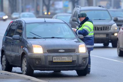 Гаишник на дороге проверяет документы у автовладельца.