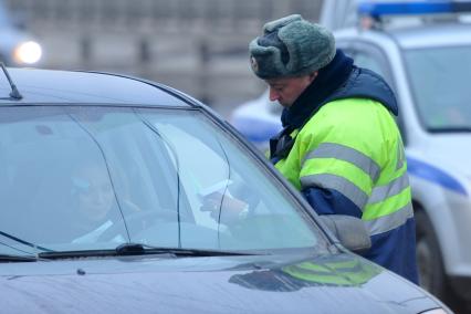 Гаишник на дороге проверяет документы у автовладельца.