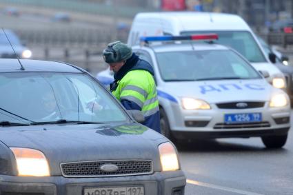 Гаишник на дороге проверяет документы у автовладельца.