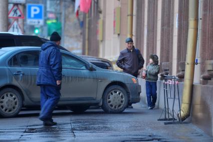 Мужчина с сыном протискиваются между припаркованными на тротуаре машинами.