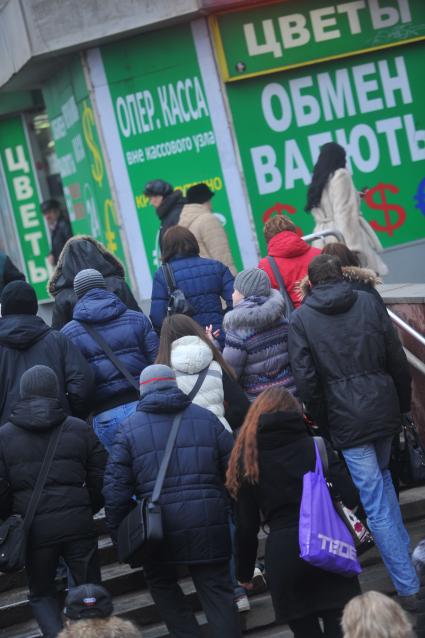 Люди идут мимо обменного пункта валют.