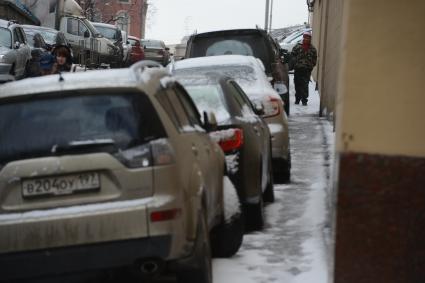 Припаркованные автомобили и пешеходы на городской улице.