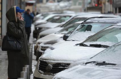 Ожидание. На снимке: женщина курит у припаркованных автомобилей.