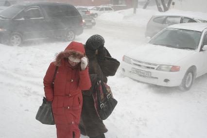 Метель, девушки идут по улице прикрывая лицо от снега.
