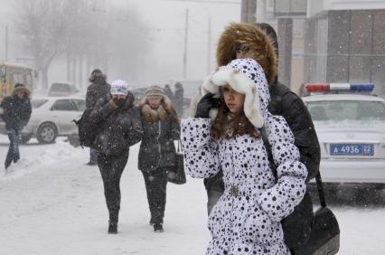 Зимняя непогода на улицах Барнаула. Люди прикрывают лица от сильного ветра со снегом.
