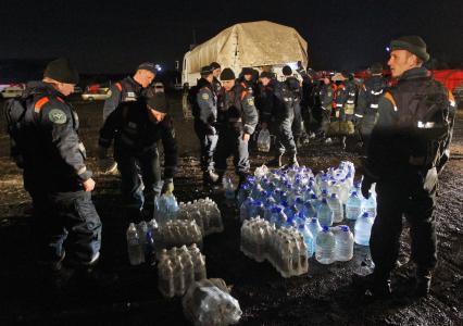 Спасатели стоят около бутылок с чистой питьевой водой.