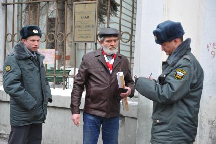 У посольства Белоруссии в Москве прошел пикет. На снимке: Полицейские проверяют документы у мужчины, который участвует в акции против смертной казни в Белоруссии. Храм Косьмы и Дамиана на Маросейке (на заднем плане).