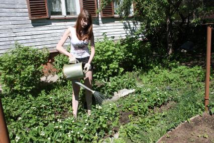 Женщина поливает грядки.