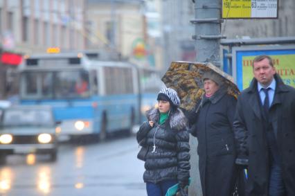 Люди ждут общественный транспорт на автобусной остановке