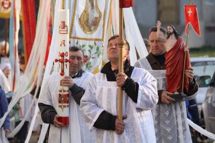 Священники совершают пасхальное шествие, несут в руках хоругви.