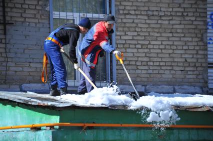 Гастарбайтеры очищают крышу от снега.