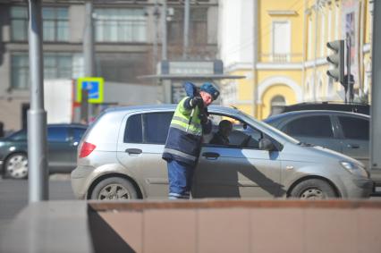 Гаишник разговаривает с водителем машины.