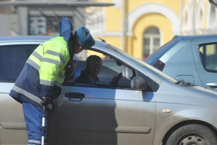 Гаишник разговаривает с водителем машины.