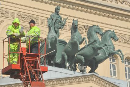 Гастарбайтеры в люльке подьемного крана перед данием большого театра.