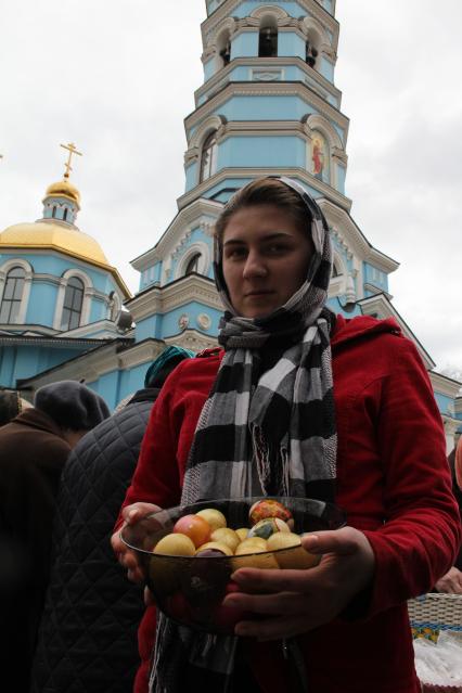 Девушка с пасхальными яйцами у храма.