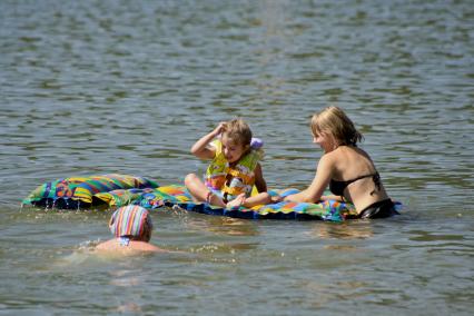 Две девочки купаются с водным матрацом.