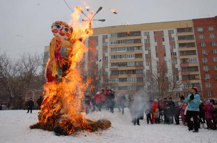 Люди на площадке сжигают чучело масленицы.