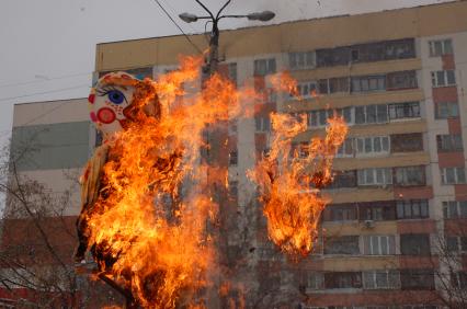 Люди на площадке сжигают чучело масленицы.