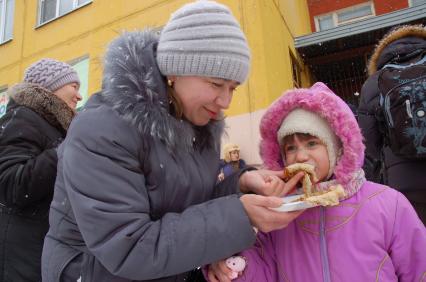 Мамаша кормит ребенка блинами.