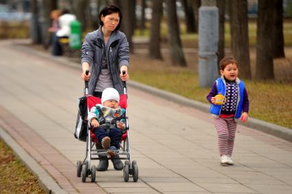 Детский парк. Усадьба Трубецких в Хамовниках. На фото: Женщина восточной внешности гуляет с детьми по парку.