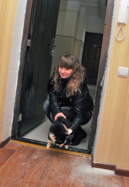 Девушка впускает в новую квартиру кошку.