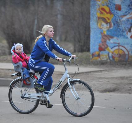 Весна в парке Сокольники. На снимке: Молодая мать везет на велосипеде ребенка.