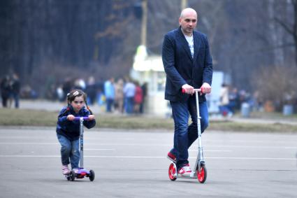 Весна в парке Сокольники. На снимке: Девочка с отцом катаются на самокате.