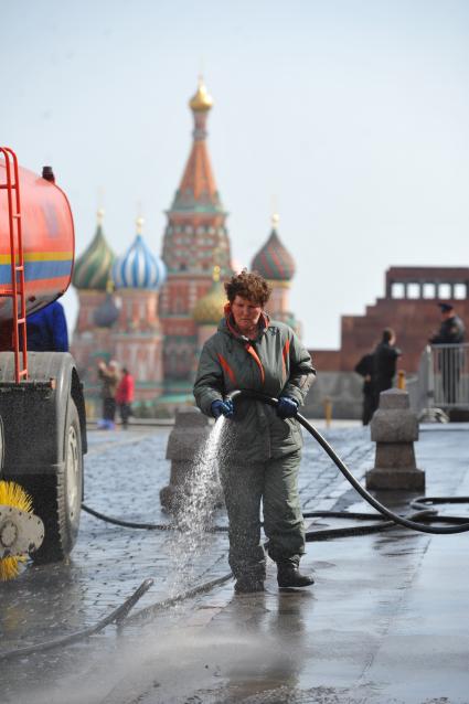 Красная площадь.  На снимке: женщина моет из шланга брусчатку и тротуар.