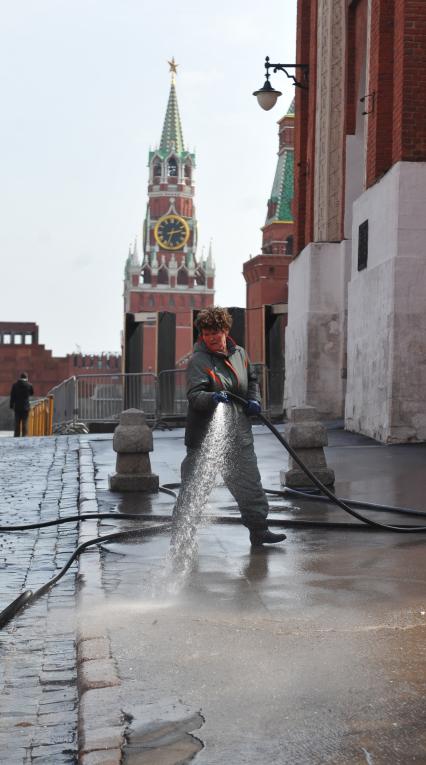 Красная площадь.  На снимке: женщина моет из шланга брусчатку и тротуар.