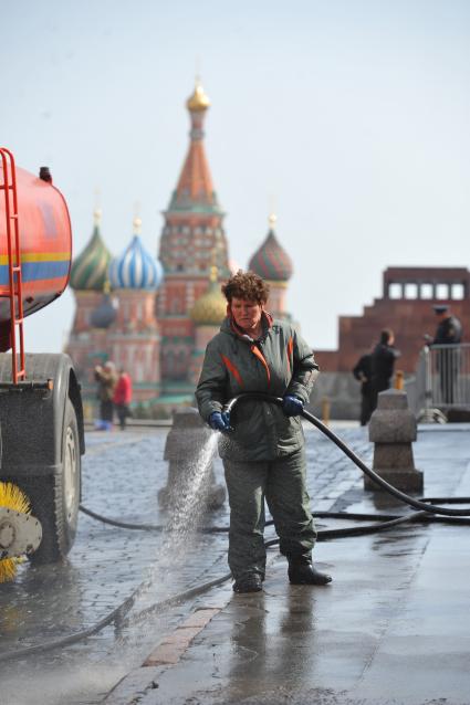 Красная площадь.  На снимке: женщина моет из шланга брусчатку и тротуар.