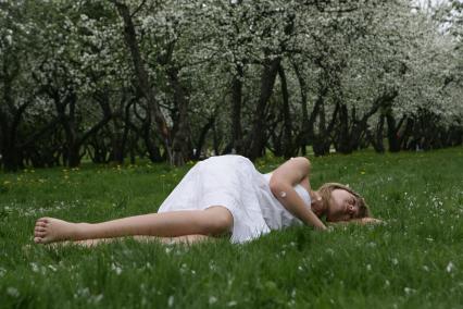 Музей-заповедник `Коломенское`. На снимке: девушка лежит на траве в яблоневом саду.