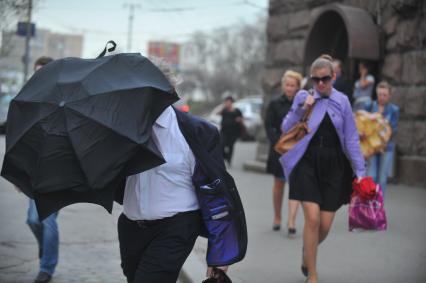 Сильный ураганный ветер в Москве. На снимке: Мужчина прикрывается от ветра зонтом.