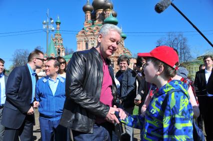 Мэр Москвы Сергей Собянин принял участие в субботнике в столичном парке `Останкино`. На снимке: Мэр Москвы Сергей Собянин общается с народом. Храм Животворящей Троицы (на заднем плане).