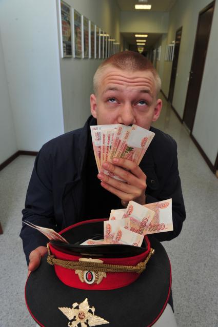 Молодой человек с деньгами в офицерской фуражке.